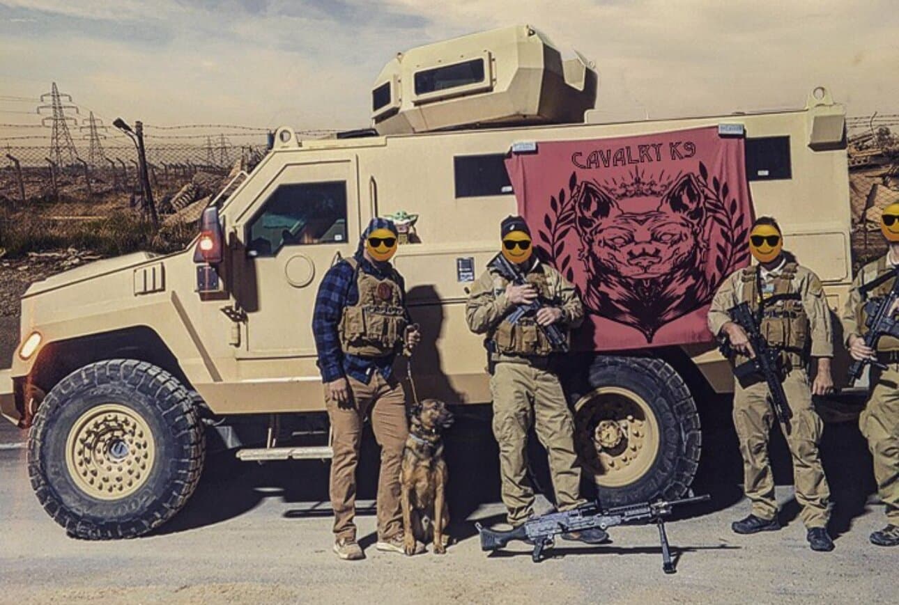 Security team with a working dog in front of an armored vehicle flying the Cavalry K9 banner